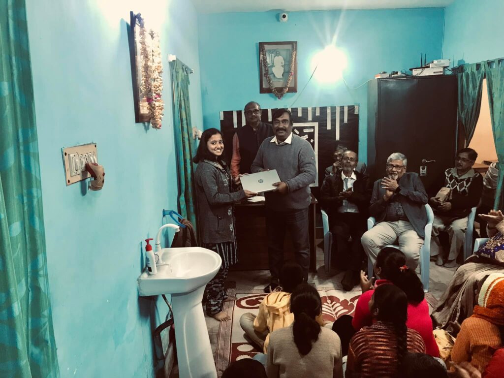 Rupa Chowni receives a laptop from a JCP Foundation member as students and guests look on, ahead of her MBBS studies at Sagar Dutta Medical College.