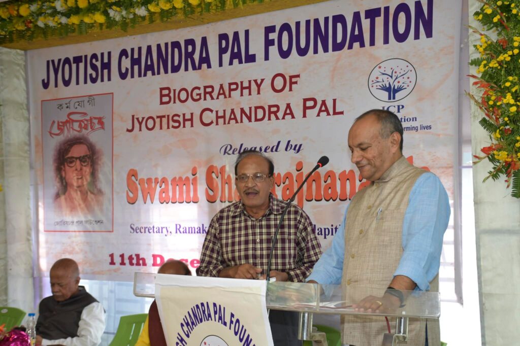 Two men stand together at the podium beneath the launch banner, one of them speaking into the microphone.