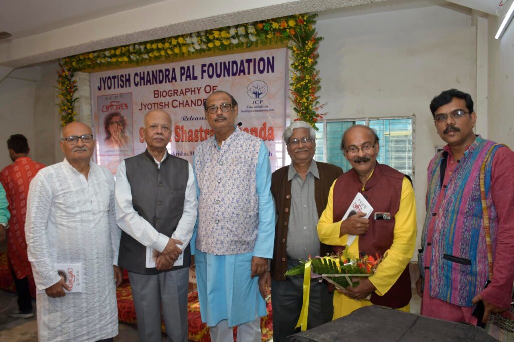 Six men stand in front of the launch banner, several of them holding copies of the newly released biography.