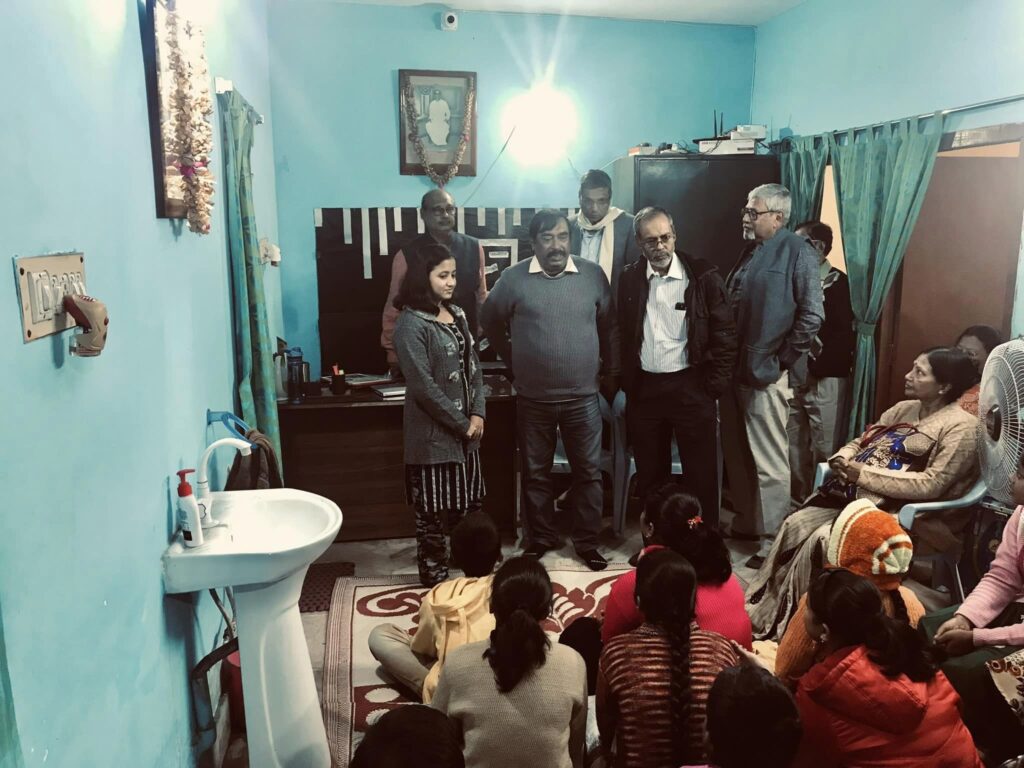 A student stands with Foundation members and guests for a photograph after the presentation, students seated on the floor around them.
